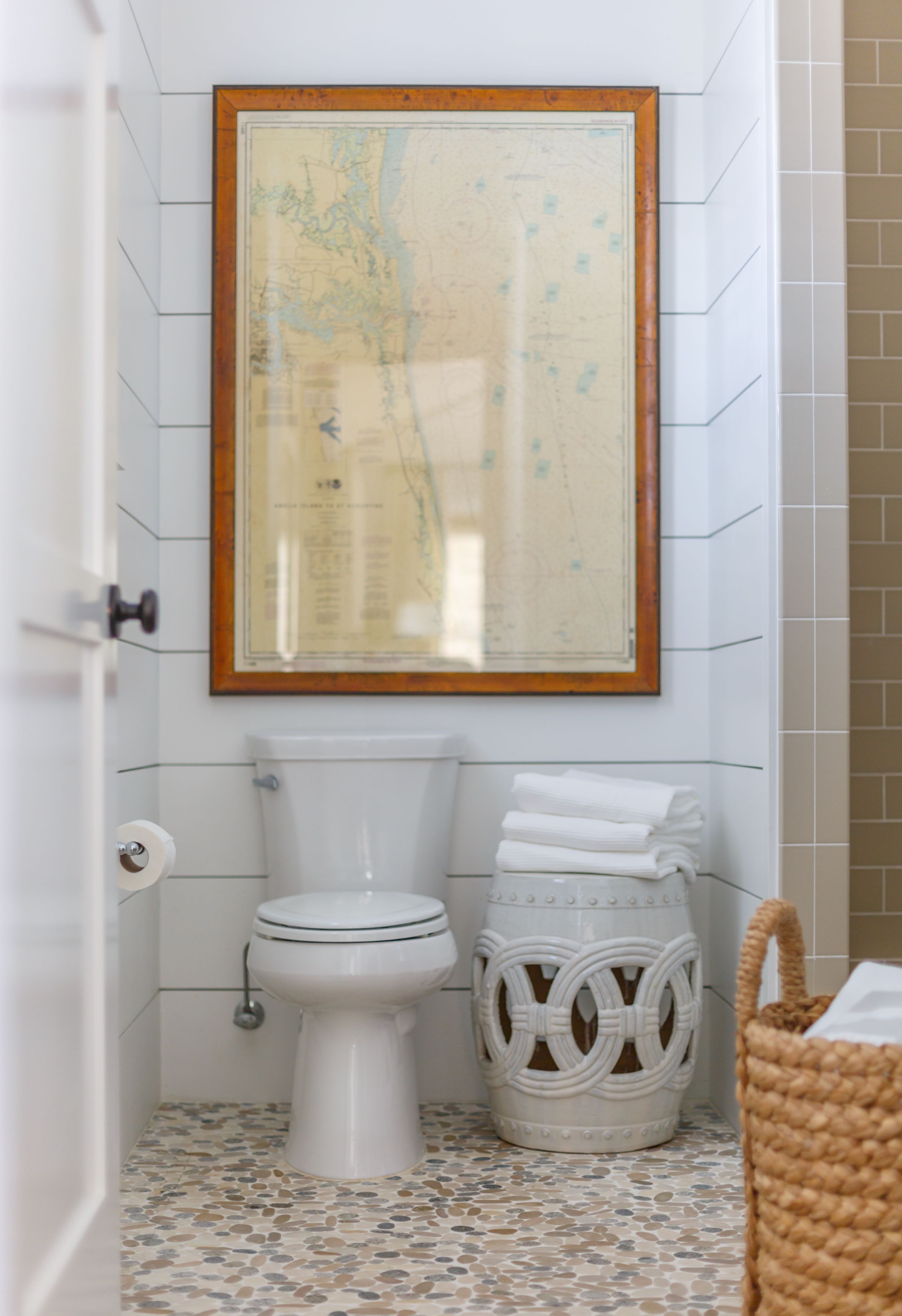 Antique framed map hanging above toilet in updated traditional bathroom.