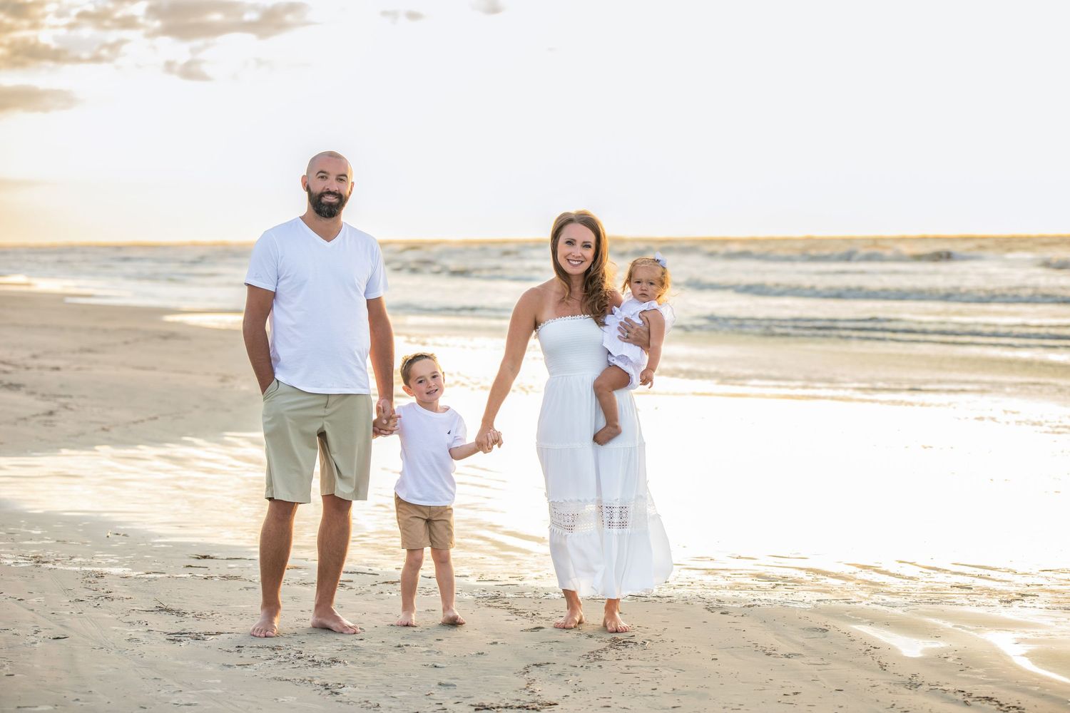 Golden sunset beach portrait of family holding hands by the ocean.