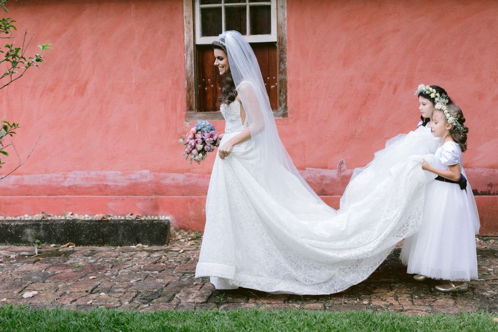 A wedding dress with a long flowing train against a coral pink wall.