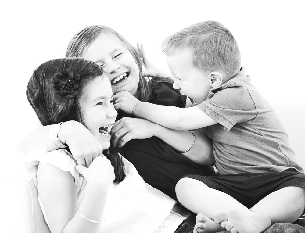Brother tickles his giggling sisters