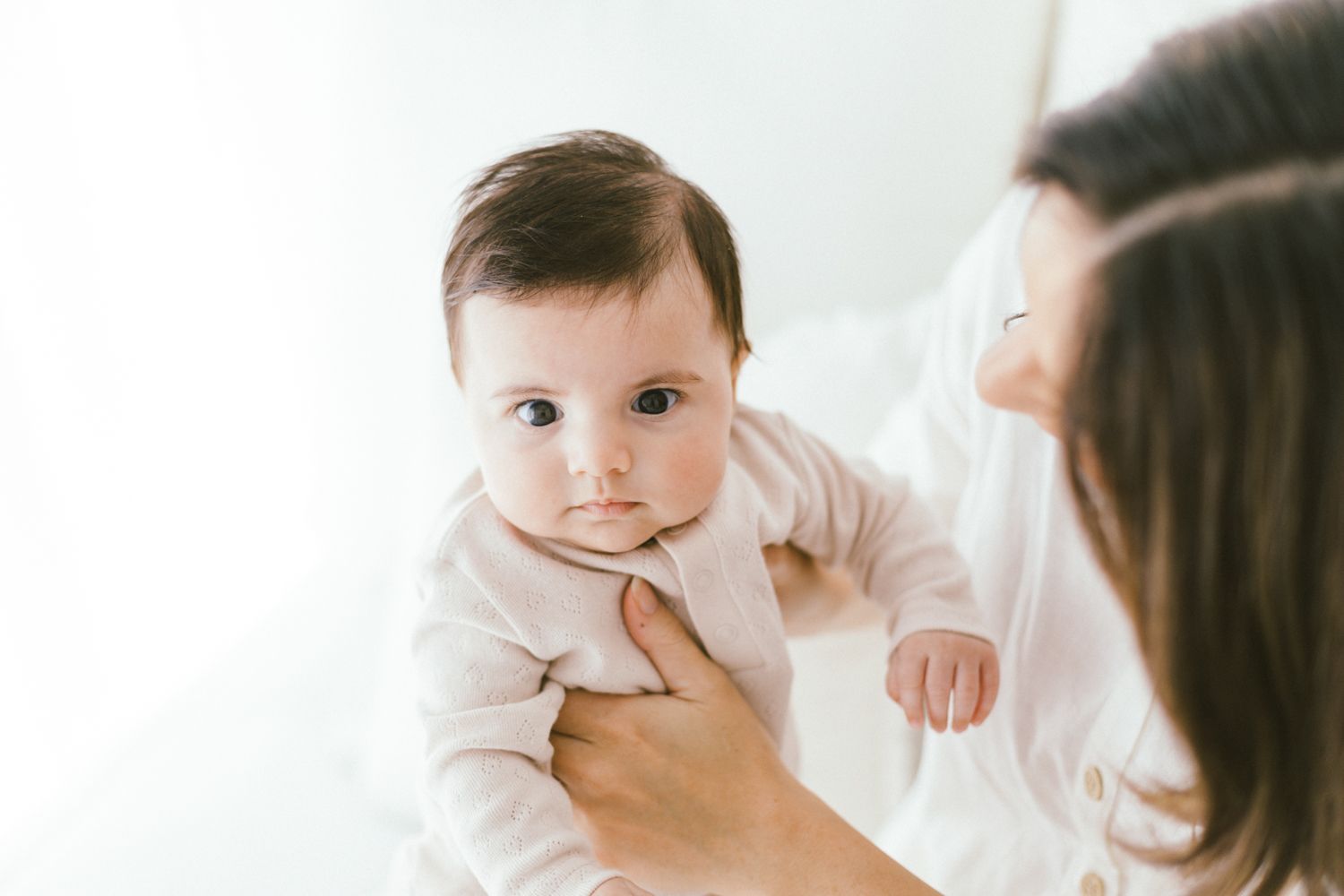 Intimate parent-child interaction captured in soft white tones.