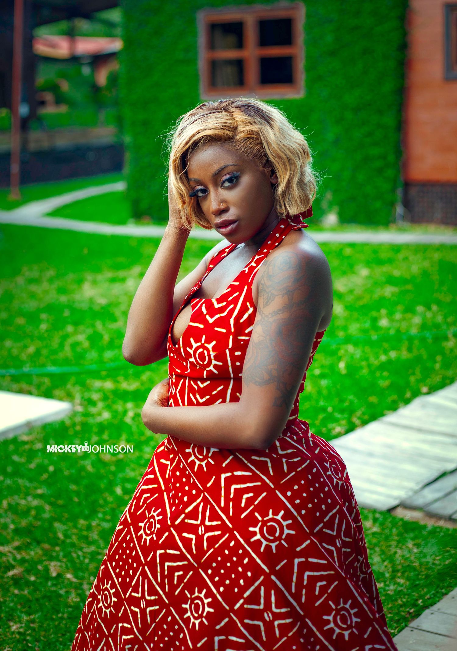 Flowing red and white patterned dress showcased against lush green garden background.