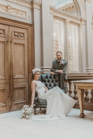 Artistic wedding portrait in an elegant vintage interior with wooden doors and tufted chair.