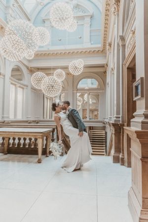 Elegant wedding scene with modern dandelion-style light fixtures in a grand white hallway.