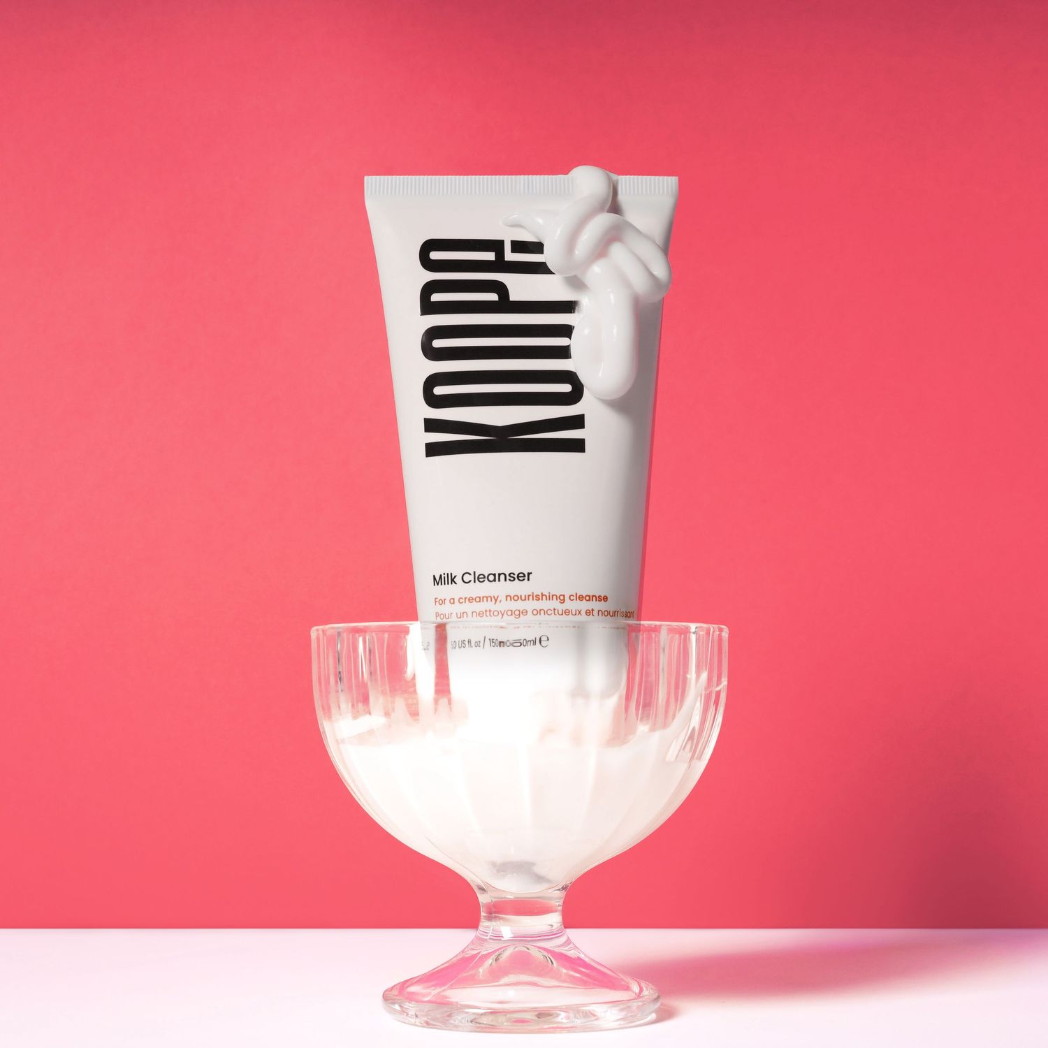White cosmetic tube labeled 'YOLPA' sitting in glass pedestal bowl against pink background.