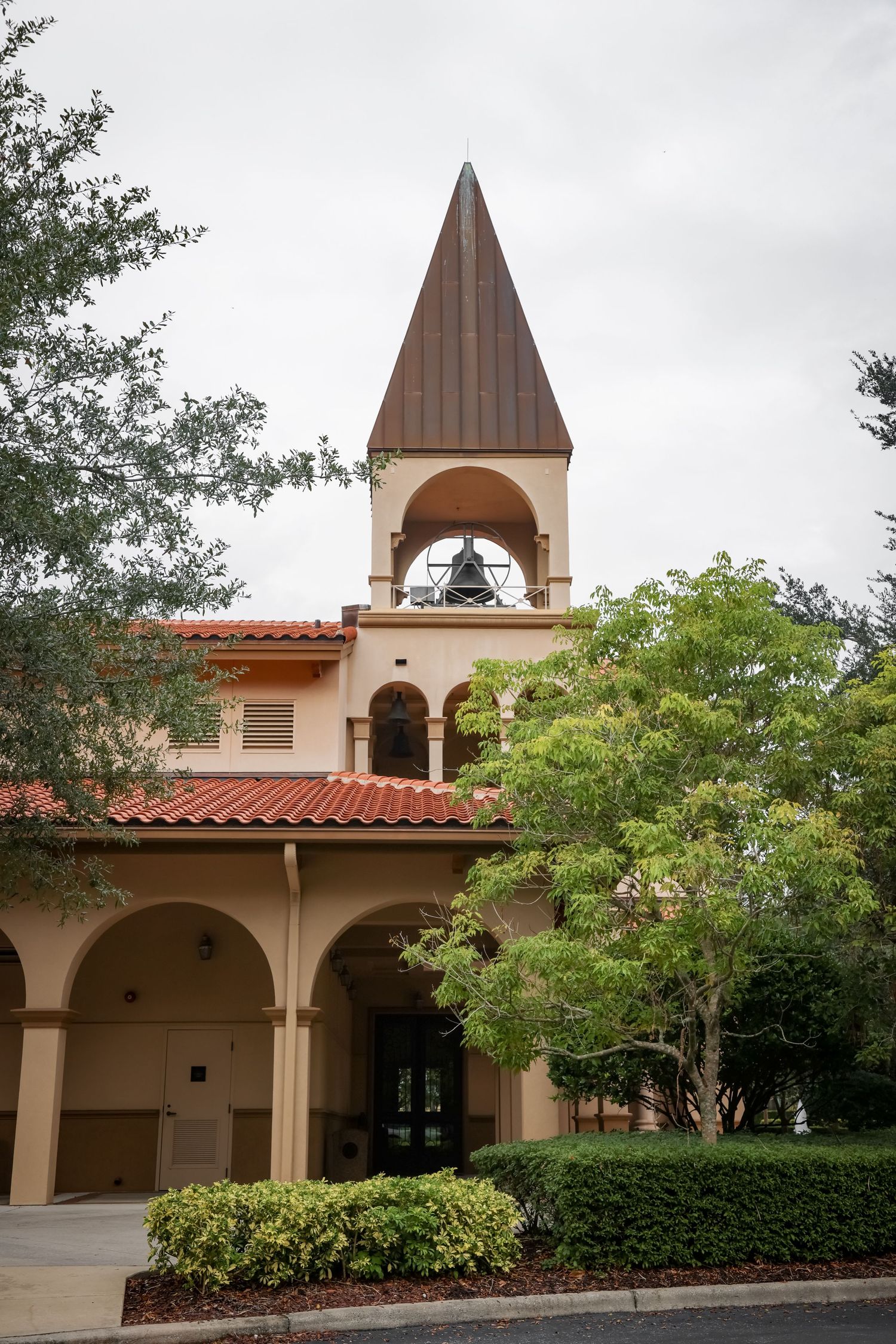 Spanish colonial style church exterior with bell tower and terracotta roof tiles.