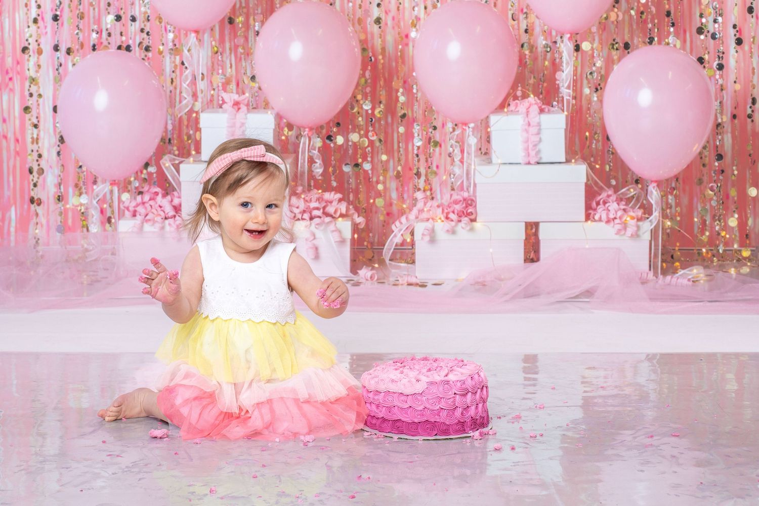 First birthday cake smash photography setup with pink balloons and tulle dress.