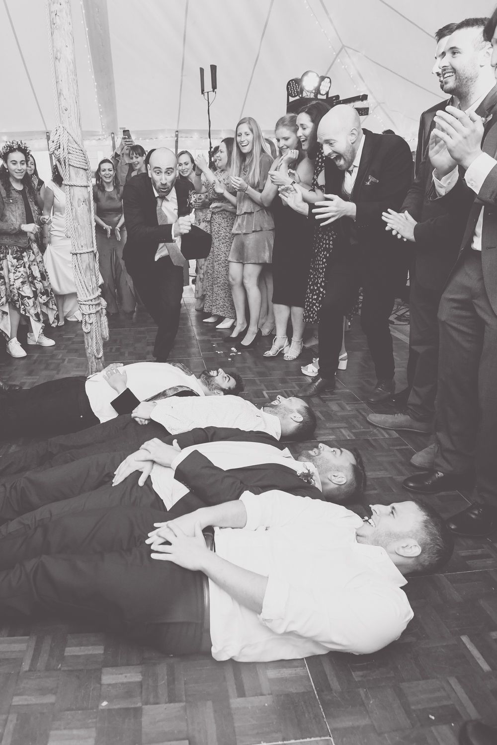 Wedding party guests dancing and laughing while others lie on dance floor.