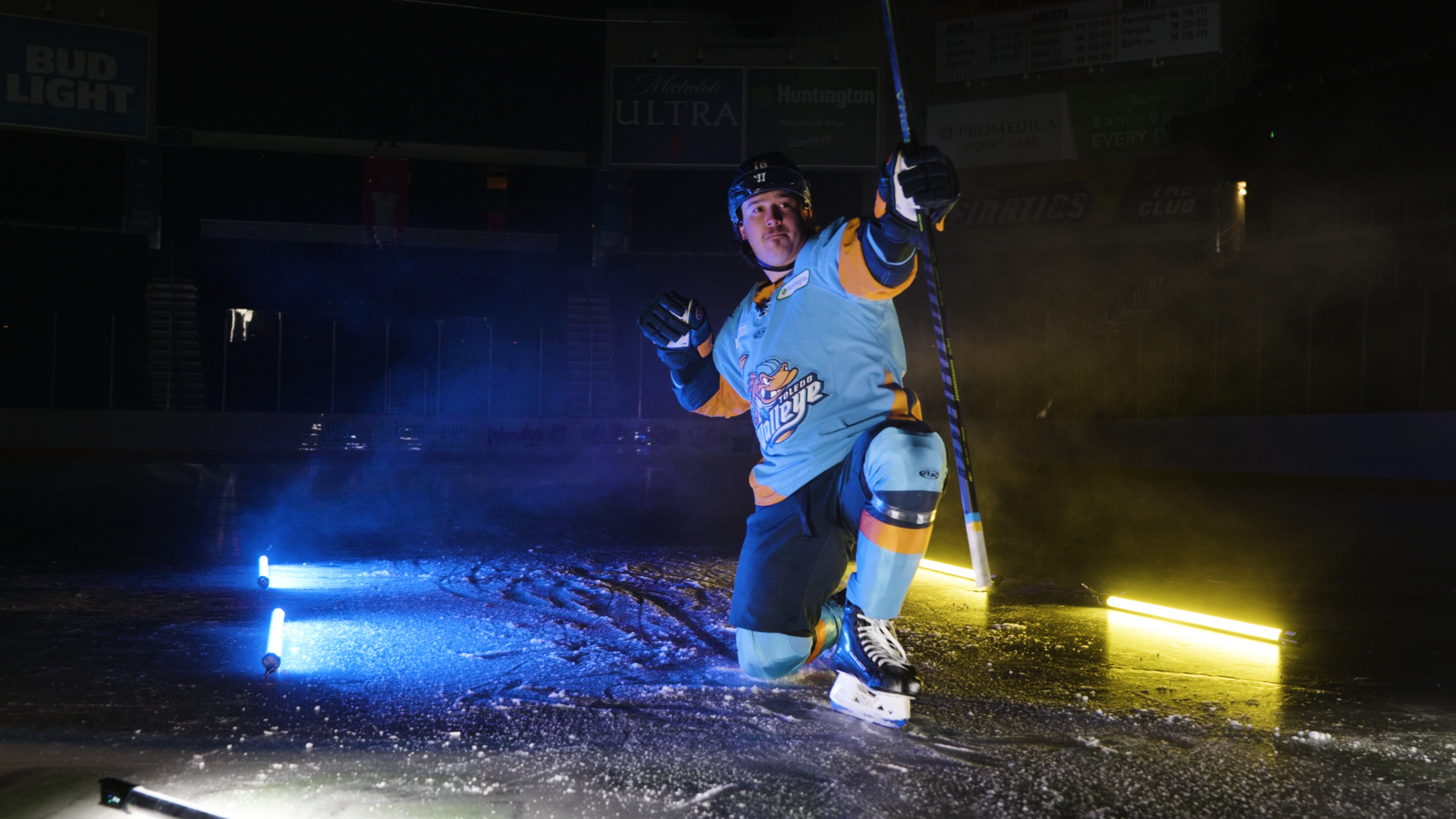 Ice hockey player skating with dramatic blue lighting and ice spray effects.