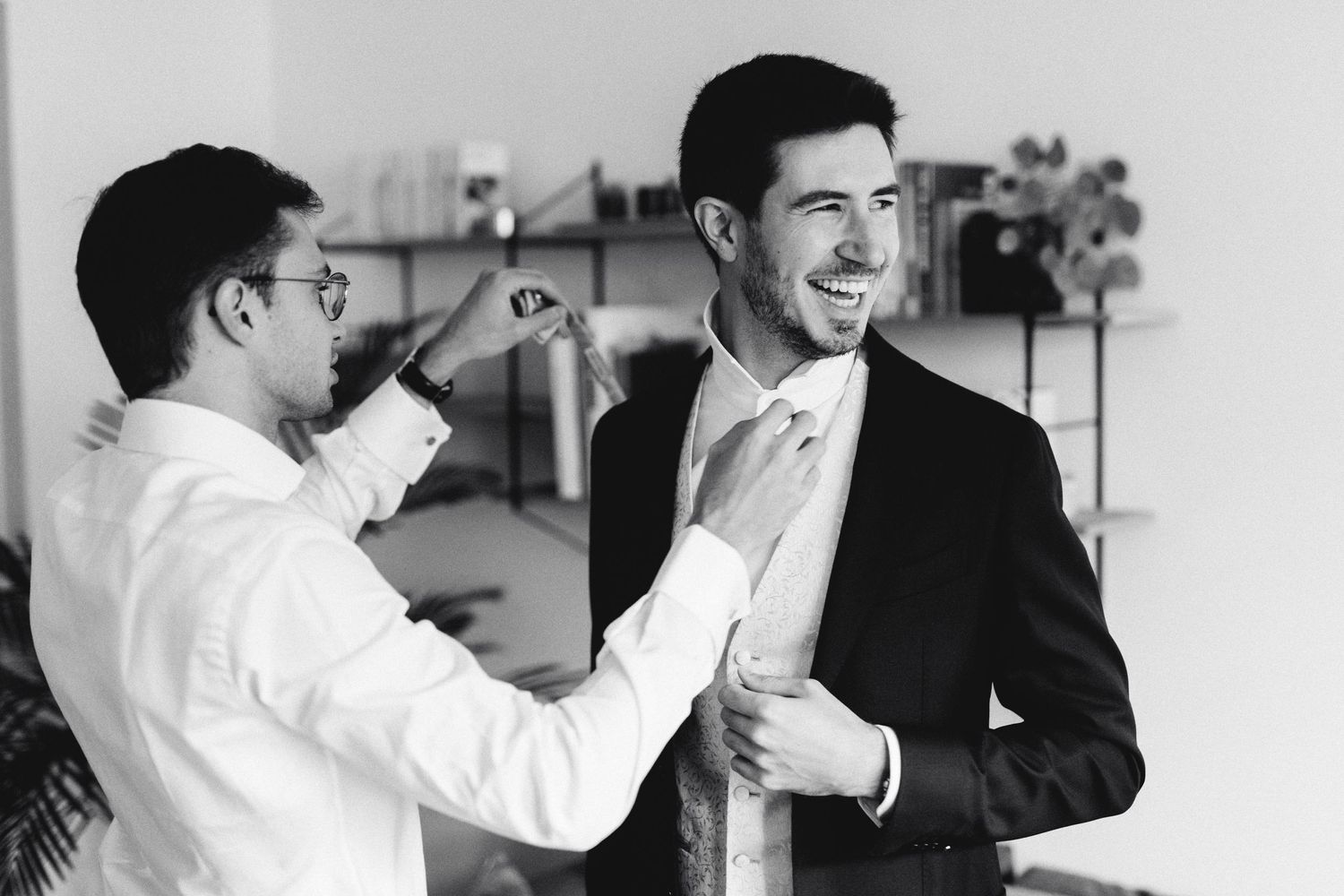 A candid moment of suit adjustments during wedding preparation.