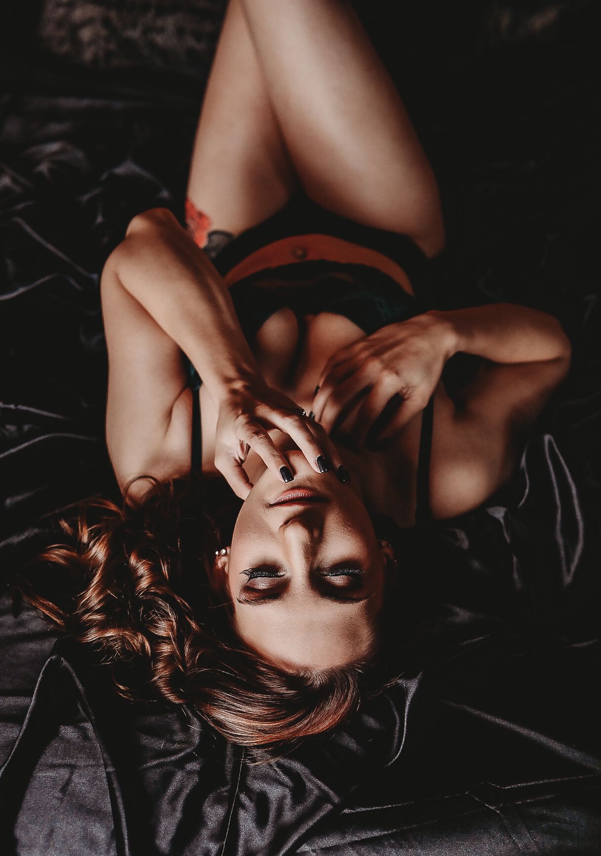 Dramatic overhead portrait with moody lighting and dark background.