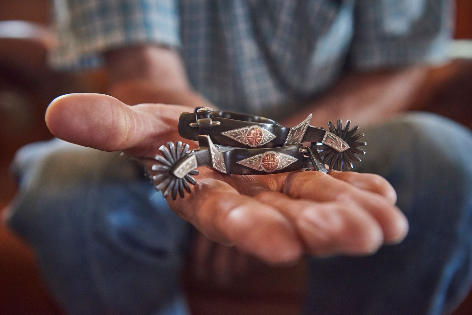 Man holding tiny child spurs in his hand