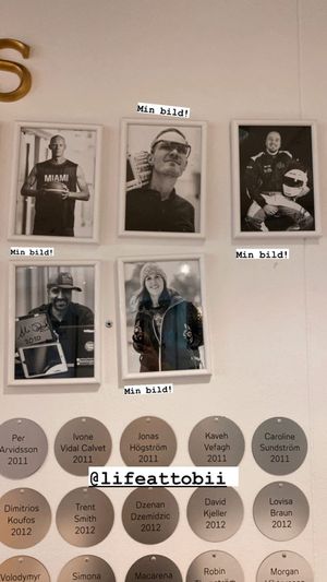 Wall display showing black and white portrait photos with name labels and dates underneath.