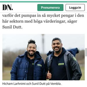 Two entrepreneurs wearing dark jackets pose outdoors at Vembla company location.