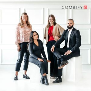 Professional group portrait of four team members in business attire in modern office setting.