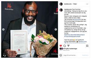 Professional holding award certificate and flowers at recognition ceremony.