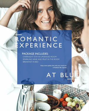 Hotel romantic package advertisement showing breakfast in bed spread with fruits and pastries.
