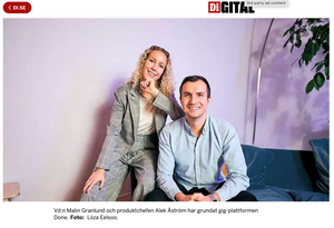 Two professionals pose in office setting with soft lighting and modern decor.