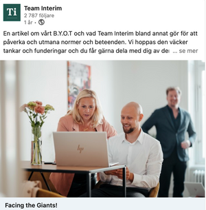 Office scene with people working at a laptop with flowers on desk.