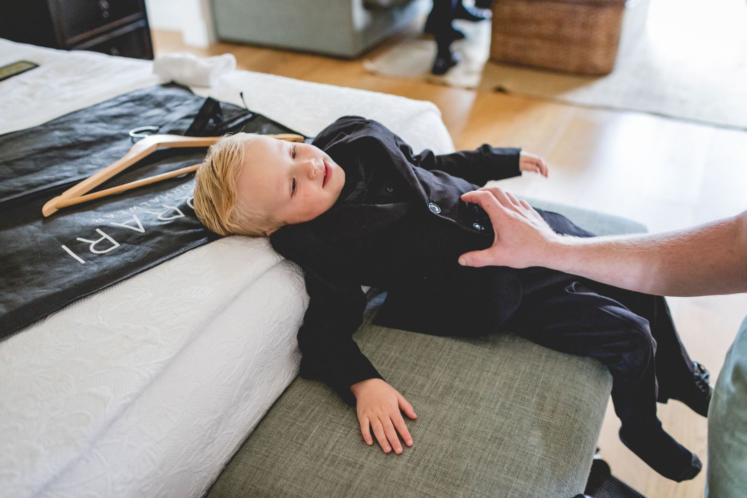 A young child in dark clothing lying on a couch.