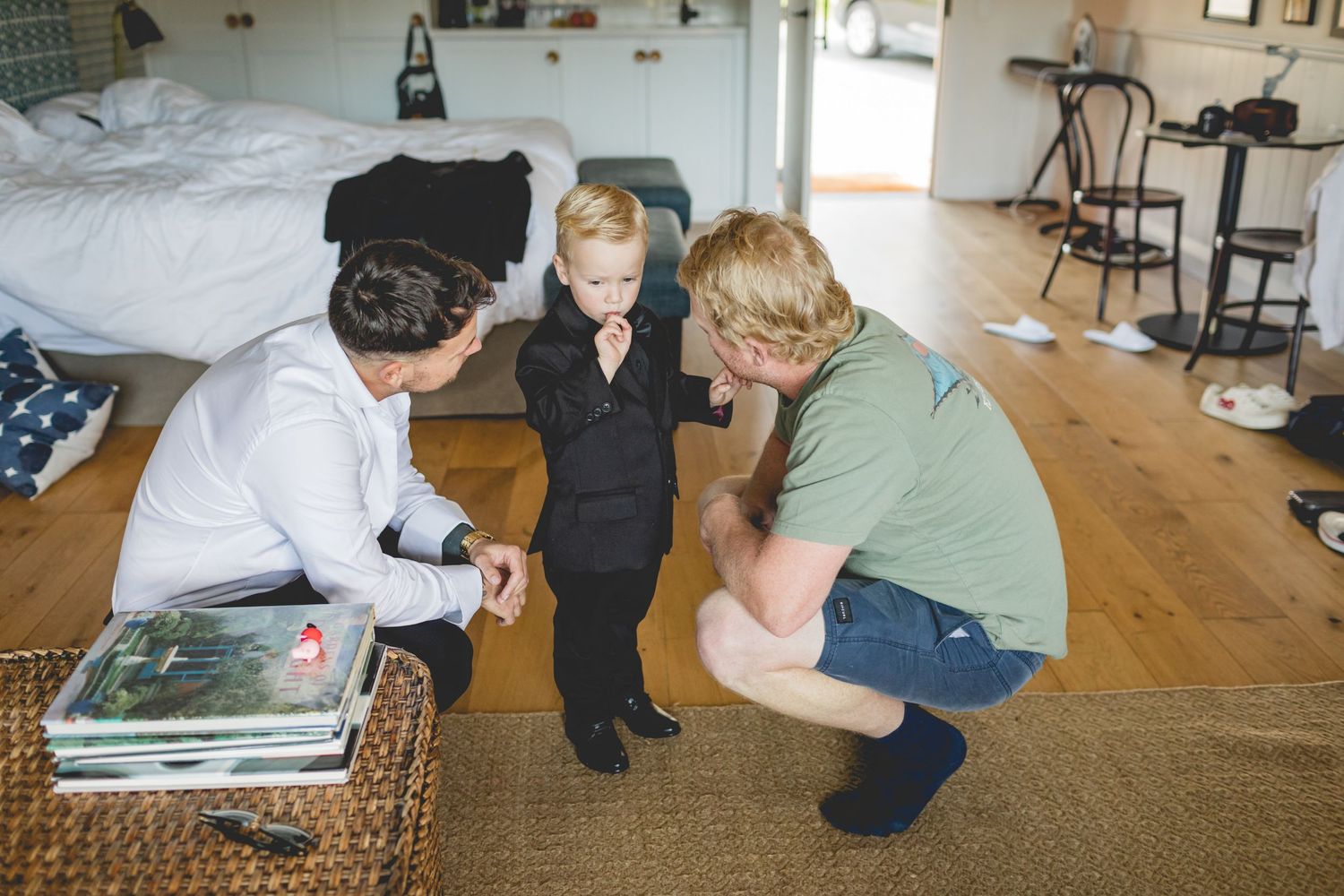 A child in formal wear interacting with adults on a wooden floor.