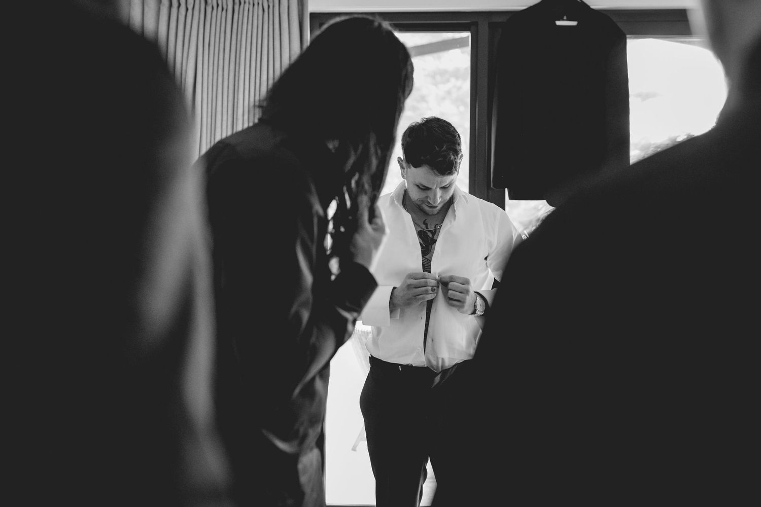 Black and white image showing people getting dressed in formal attire.