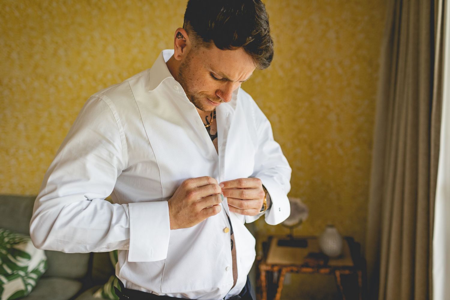 A person in white dress shirt buttoning up their sleeve.