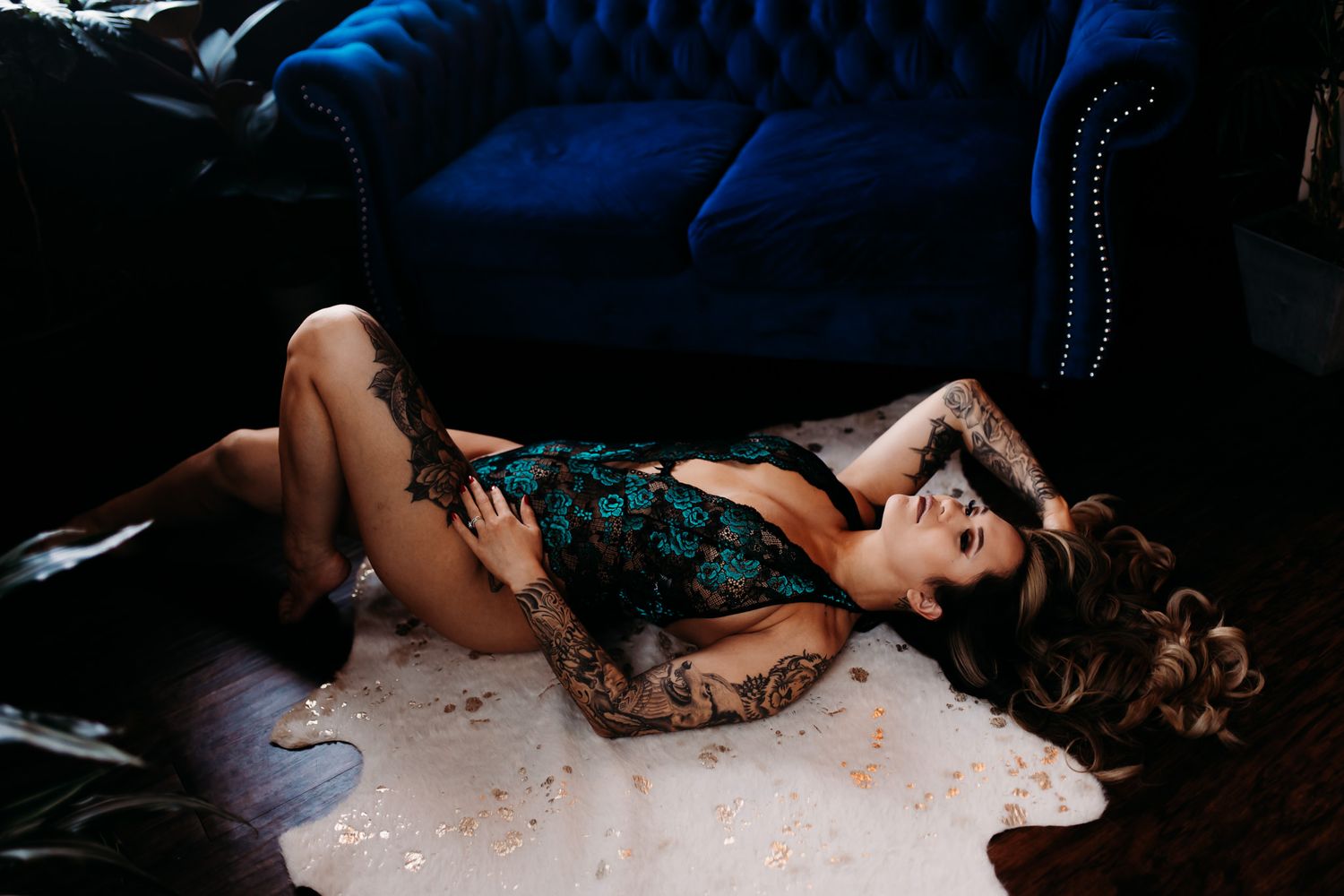 Dramatic boudoir photo on blue velvet couch with teal lace lingerie.