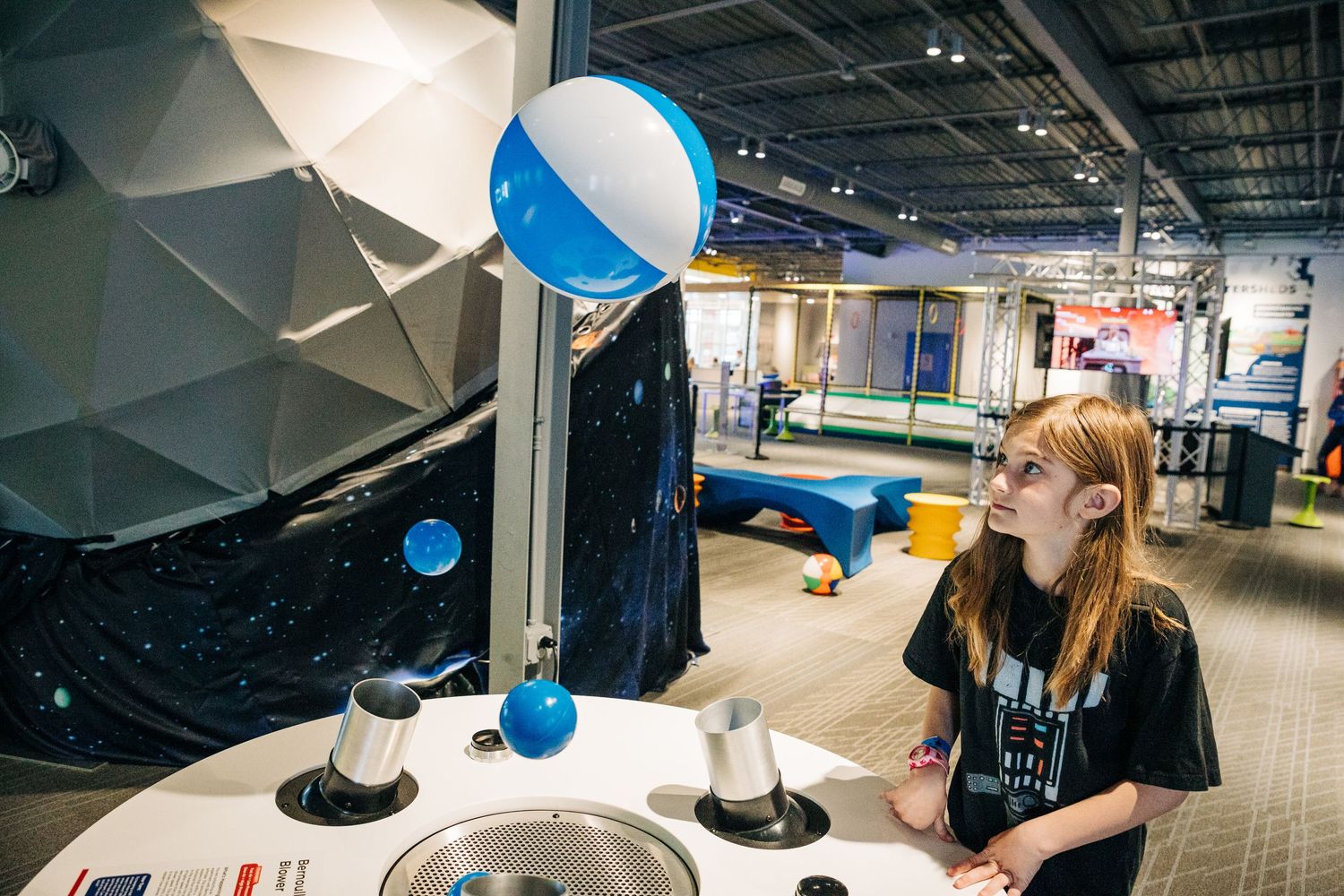 Girl watching balls hover at Monroe Science Center