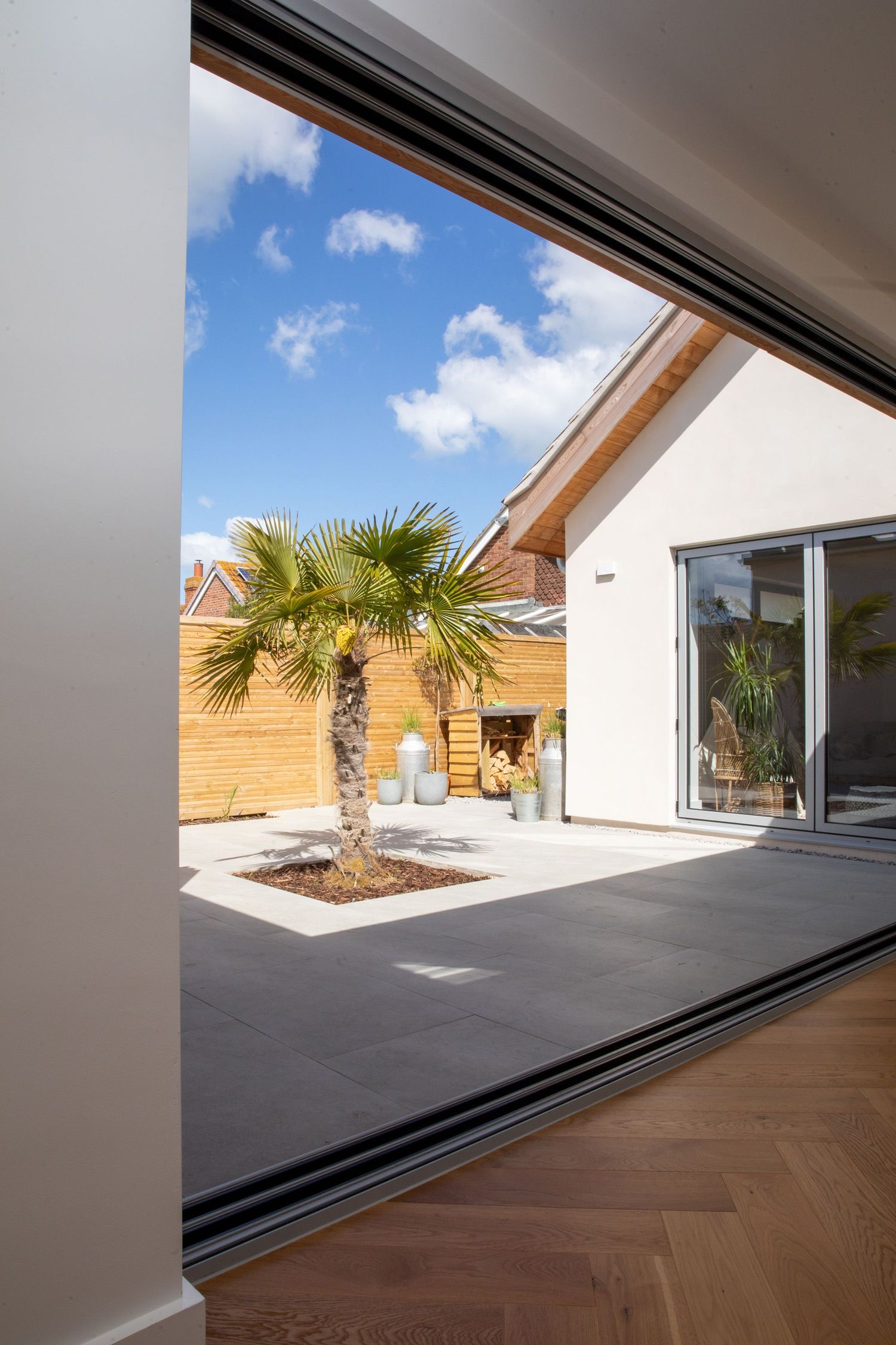 View through sliding door frame to courtyard with palm tree and concrete patio.