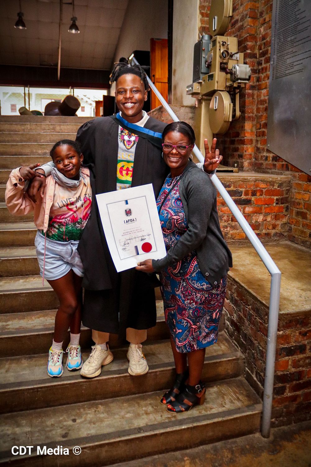 Graduation photography, graduation shoot with a degree certificate, wearing gowns and holding their degrees. Graduate with family