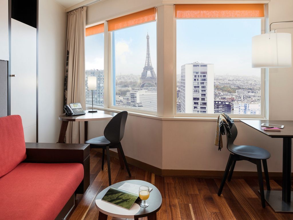 A modern hotel room interior with orange blinds and stunning Eiffel Tower view.