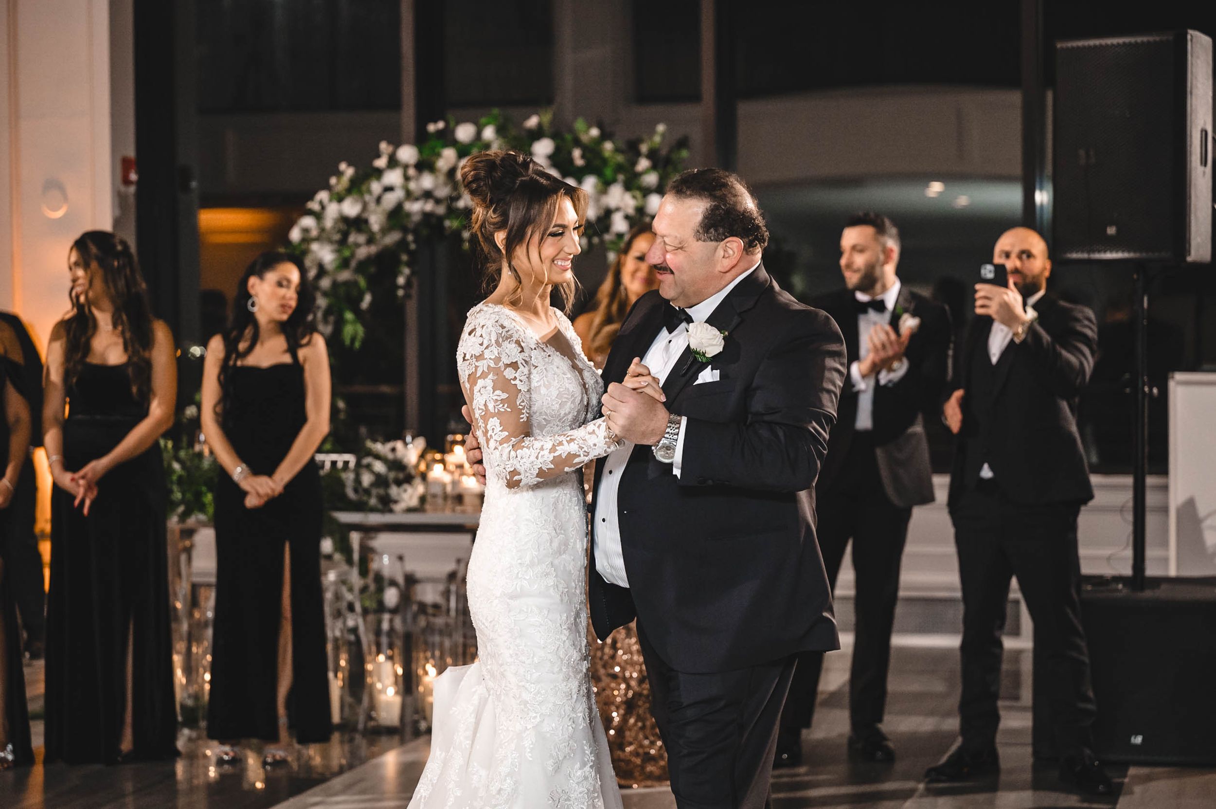 Couple dances together during an elegant wedding reception with guests watching in formal attire.