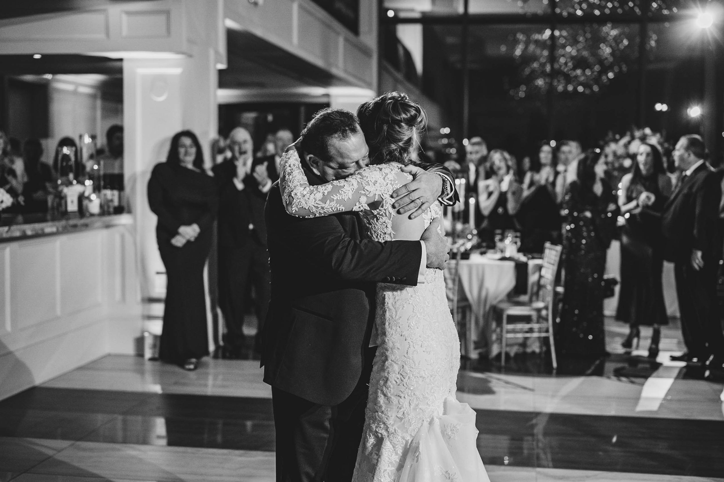 Romantic dance moment captured at an indoor wedding reception with twinkle lights and floral decor.