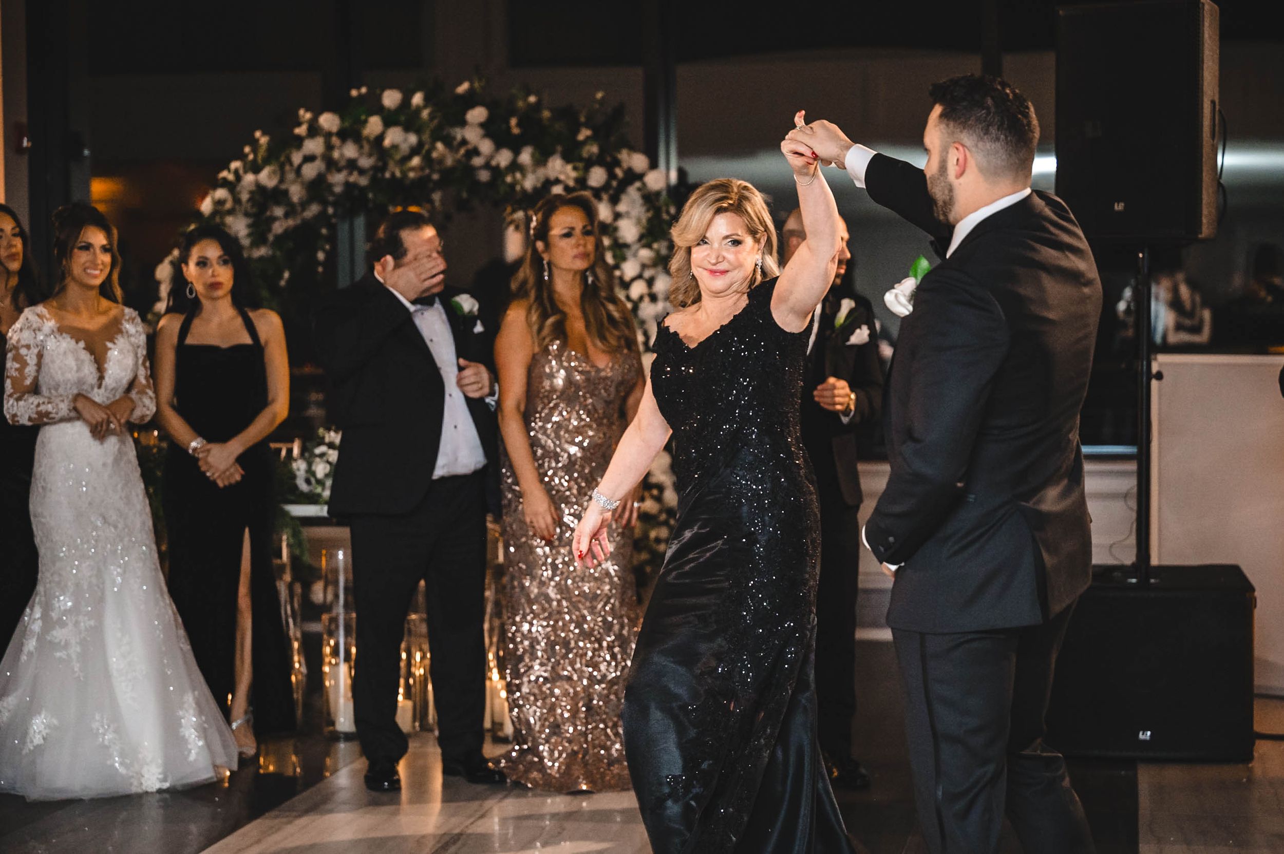Wedding reception dance floor filled with guests in formal attire enjoying the celebration.