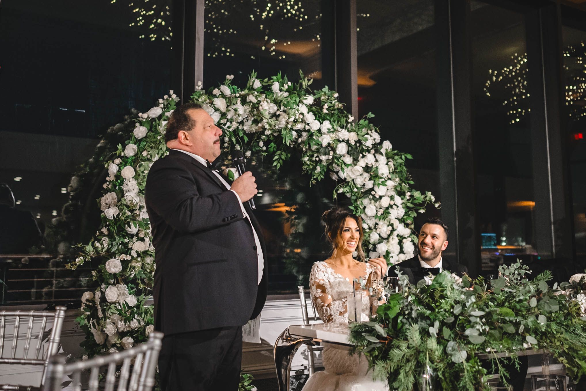Elegant wedding reception venue decorated with white floral arrangements and greenery.