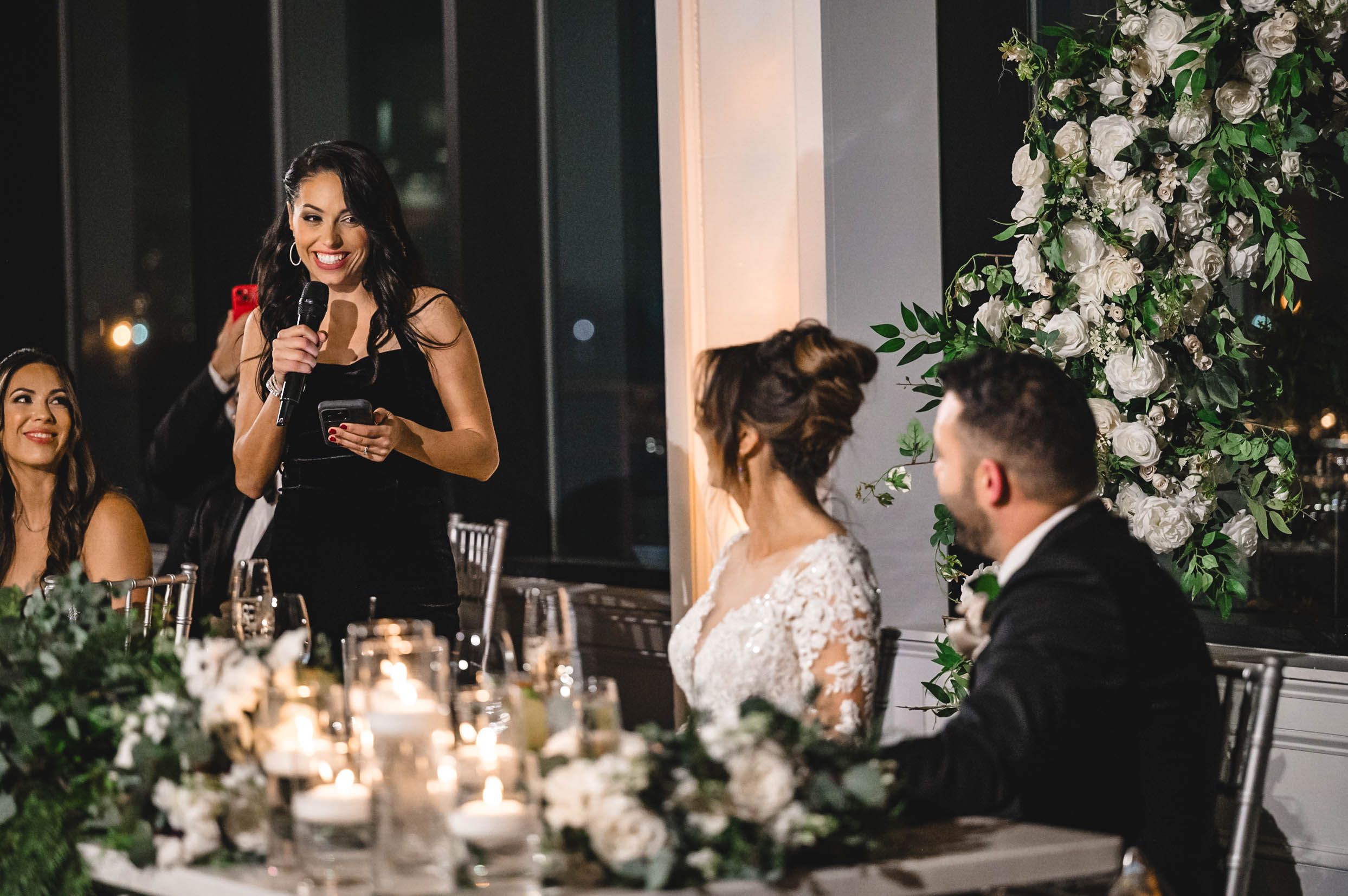 Candlelit wedding reception tables adorned with elegant white floral arrangements.