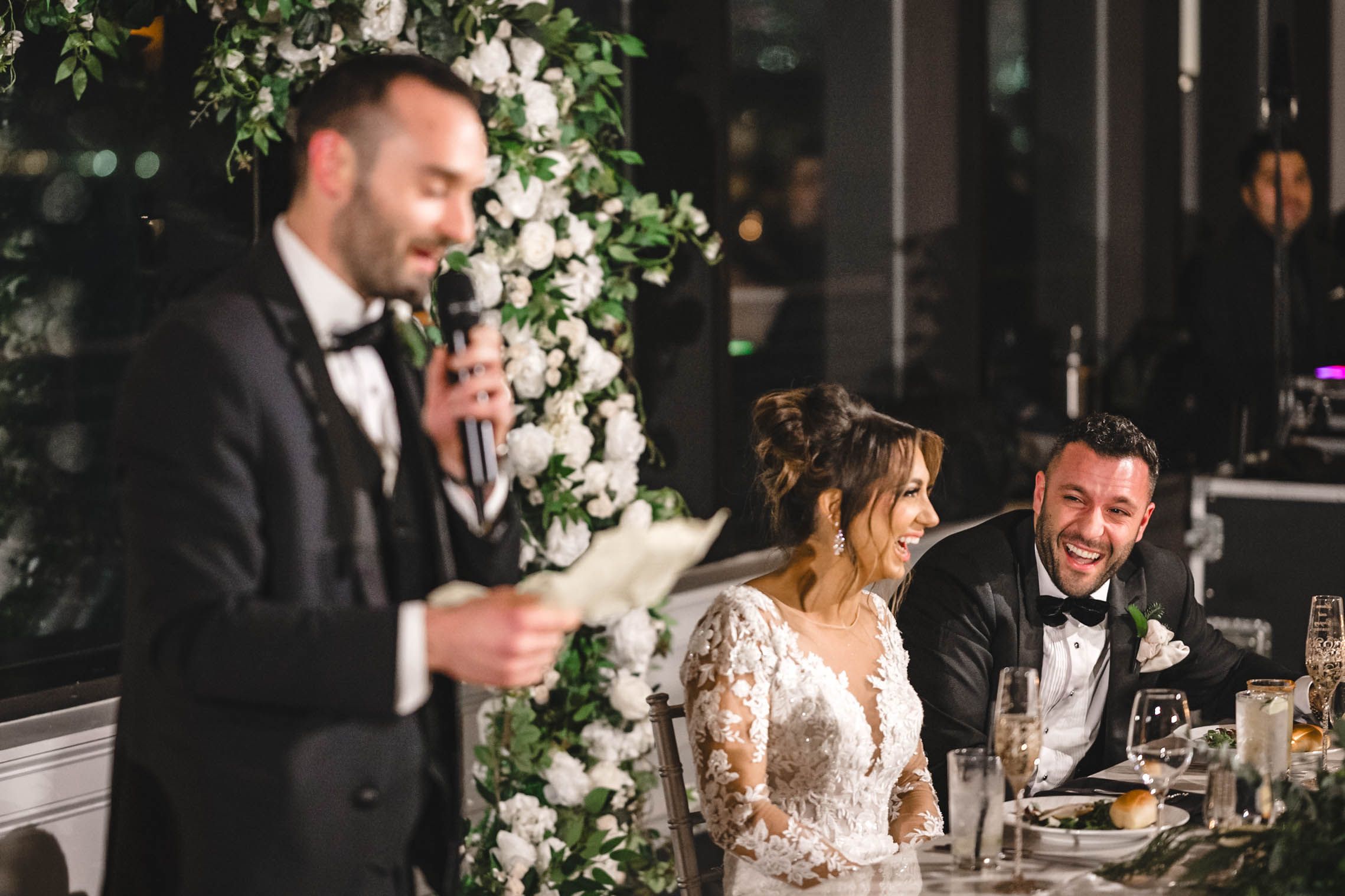 Wedding reception table setup with lush white floral centerpieces and romantic lighting.
