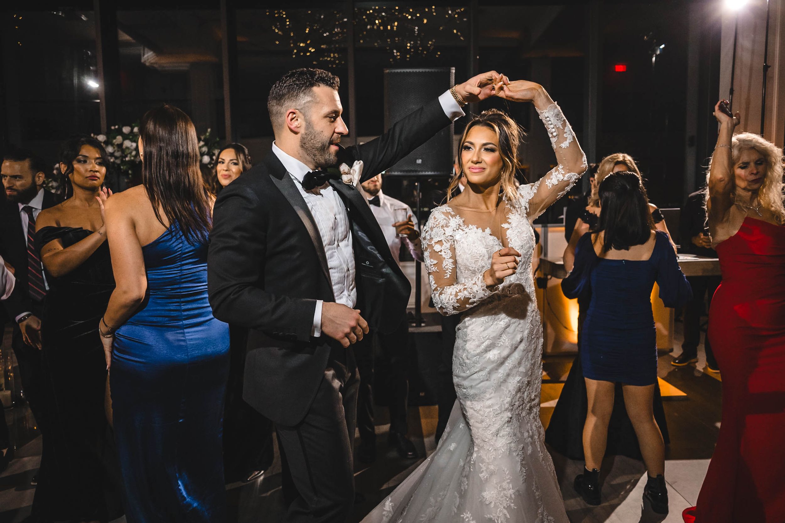 Elegant wedding reception venue with guests dancing under warm lighting and decorative elements.