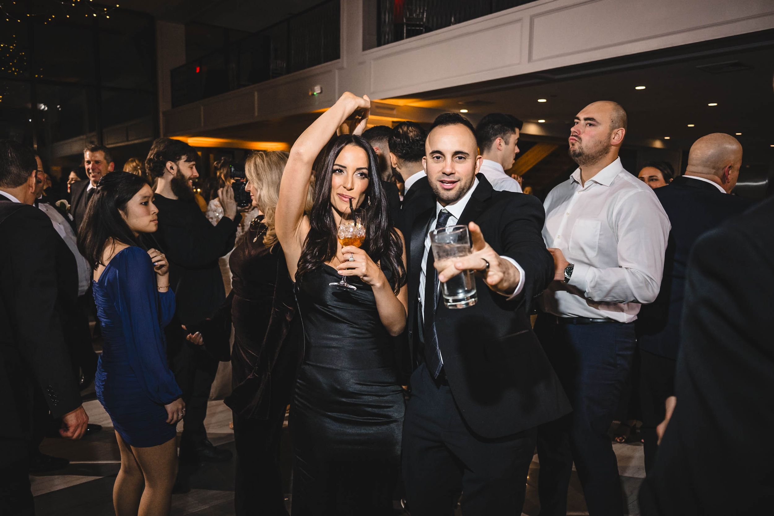 Candid moments of wedding guests dancing and celebrating at an indoor reception.