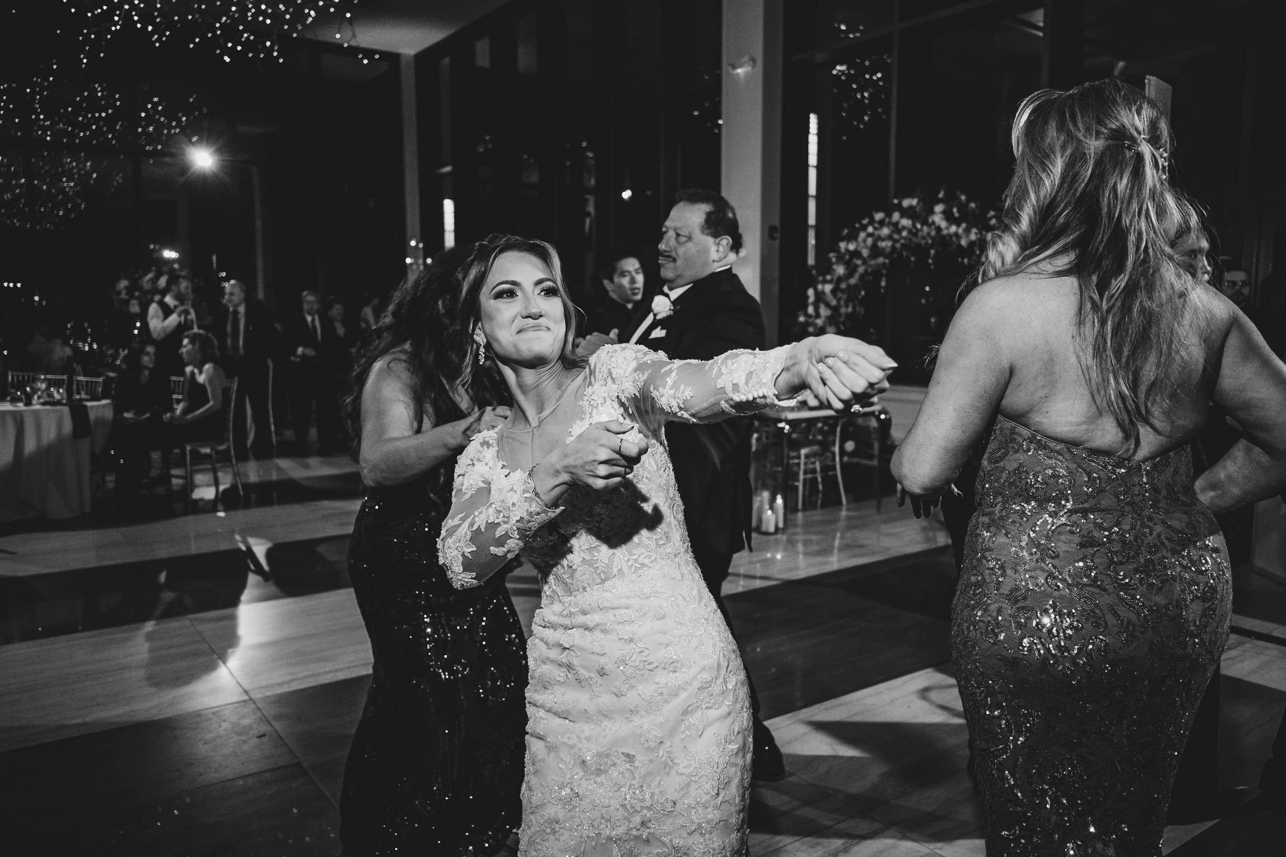 Wedding reception dance floor filled with celebrating guests under twinkling lights.