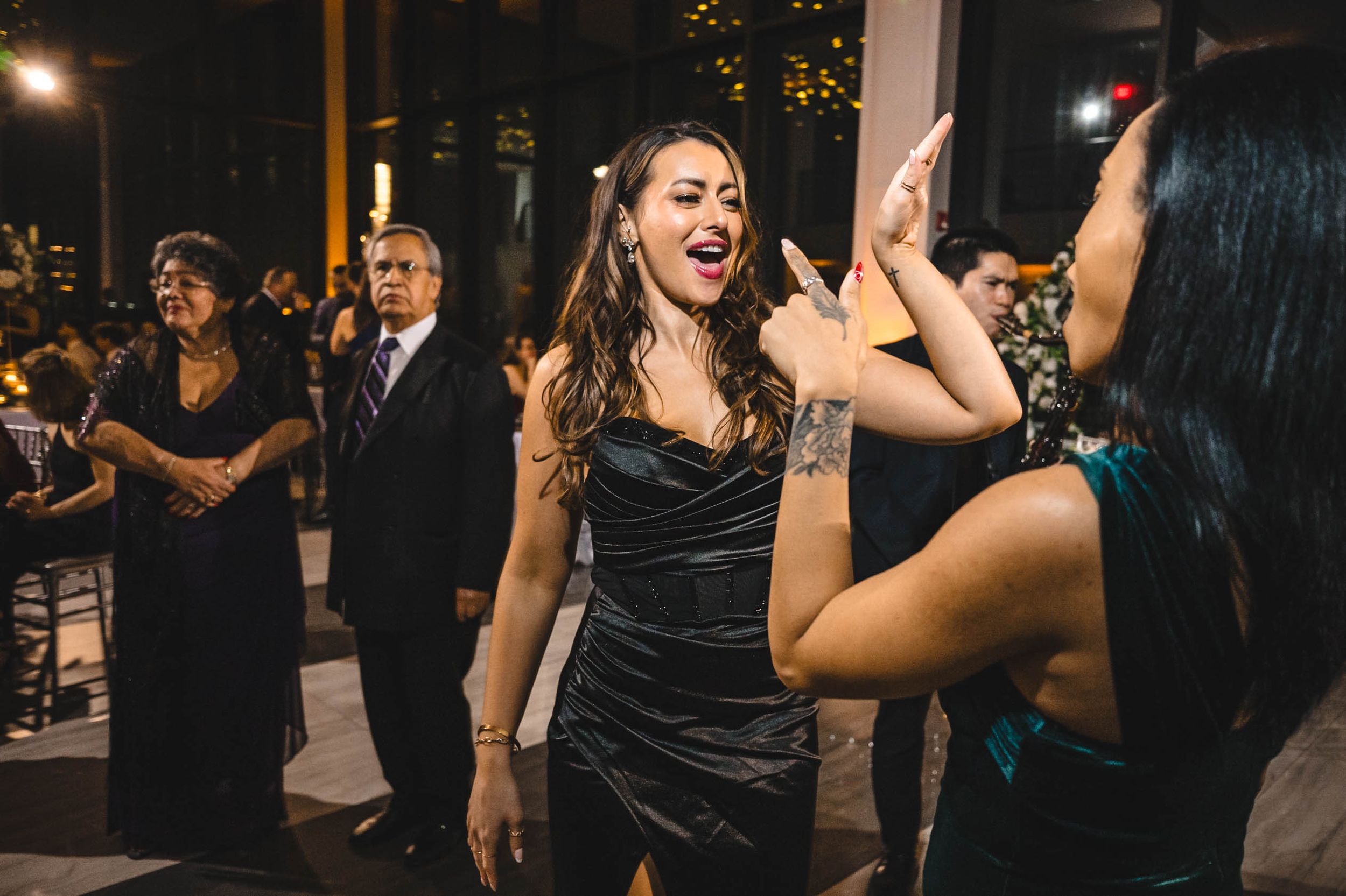 Wedding guests dancing and celebrating at a lively reception party with festive lighting.