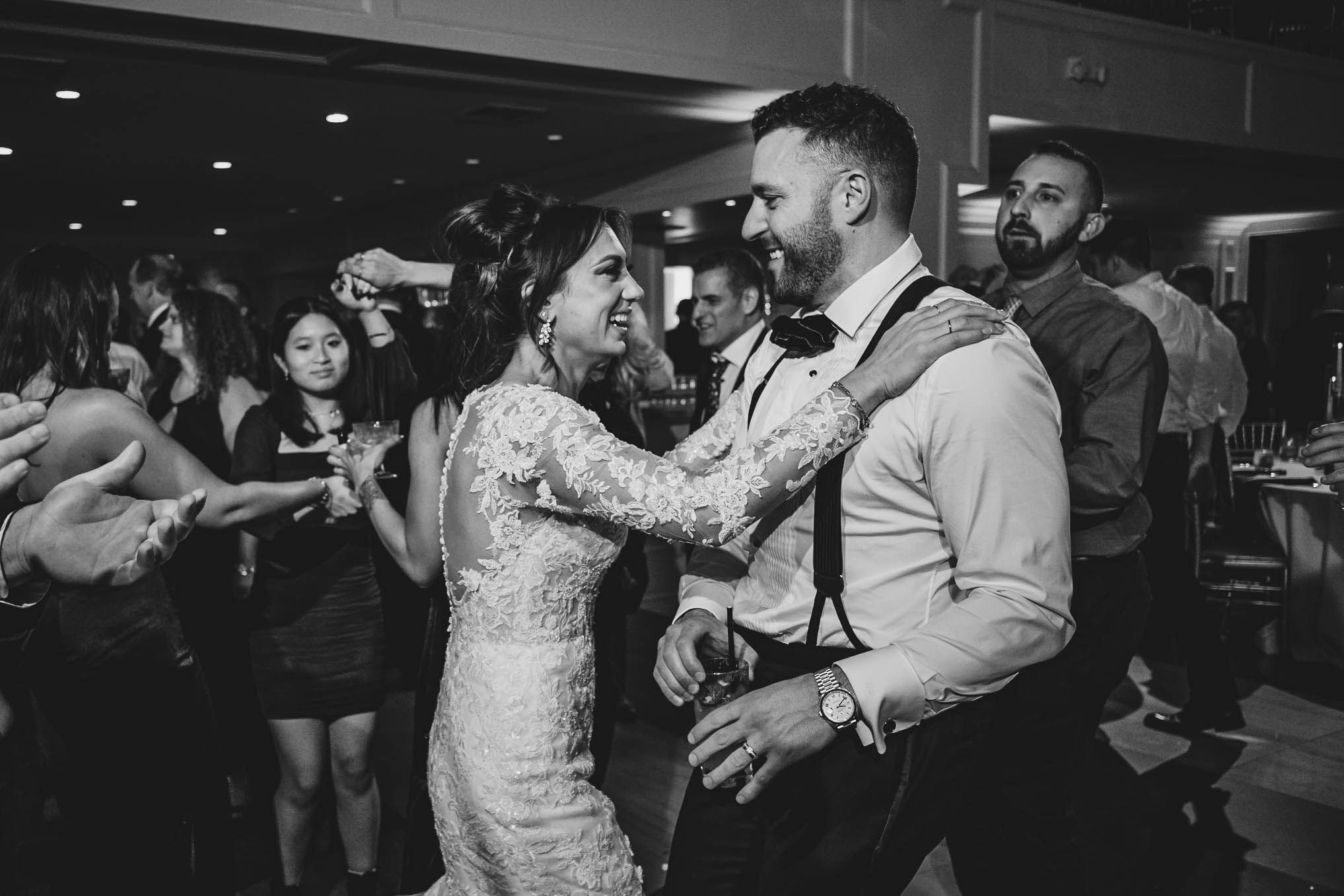 Black and white photo of wedding guests dancing and celebrating at a reception.