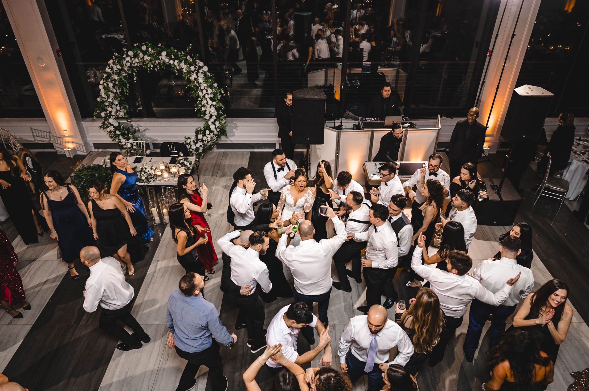 Large group of wedding guests dancing together in a circle at the reception.