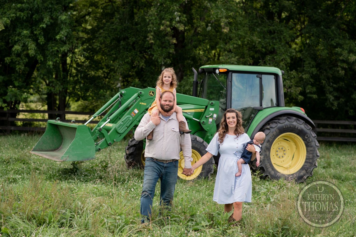 Family walks together on their farm with a green tractor in the background.
