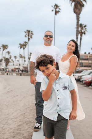 Candid beach photoshoot moments with family playing in the sand near palm trees.