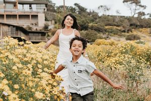 Playful moment captured in field of yellow wildflowers along California coastal path.