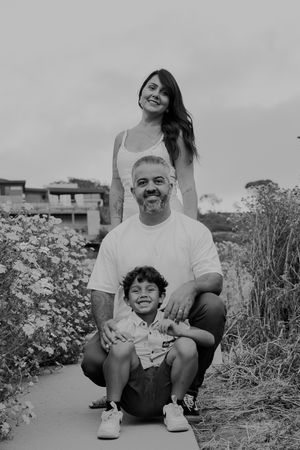 Black and white portrait of family stacked vertically on coastal path among flowers.