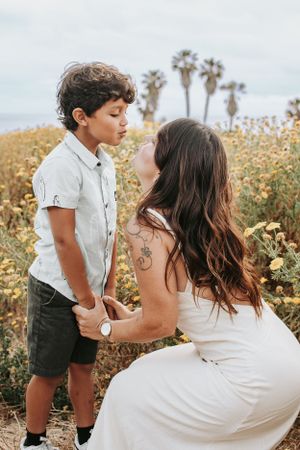A tender moment between parent and child surrounded by wildflowers with palm trees in the background.