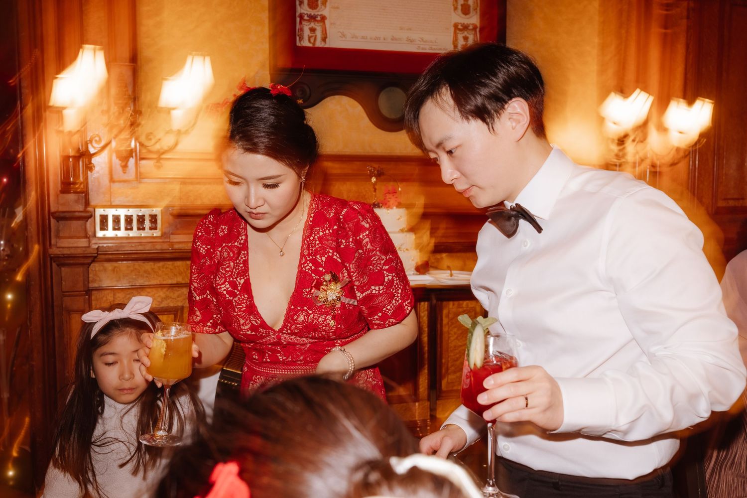 Family gathering at reception with traditional red dress and white formal attire.